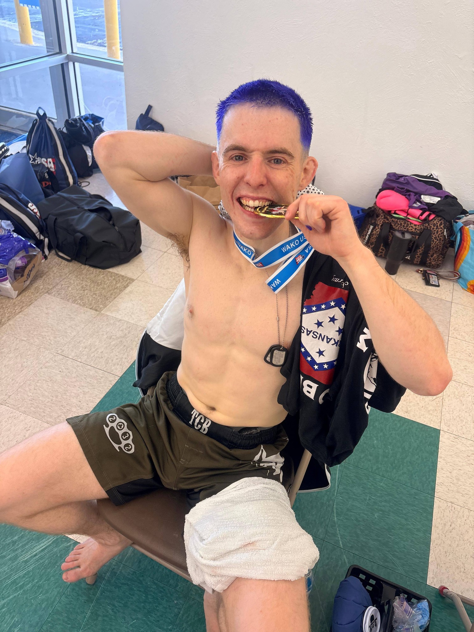 TCB fighter biting his WAKO USA gold medal, Arkansas flag jersey draped over his shoulders