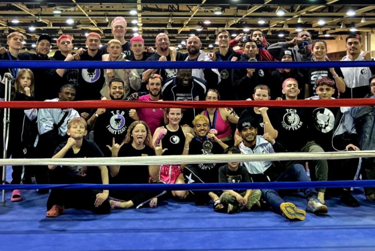 The TCB Fight Team gathered inside the ring at the WAKO USA Nationals venue with the team flag held wide