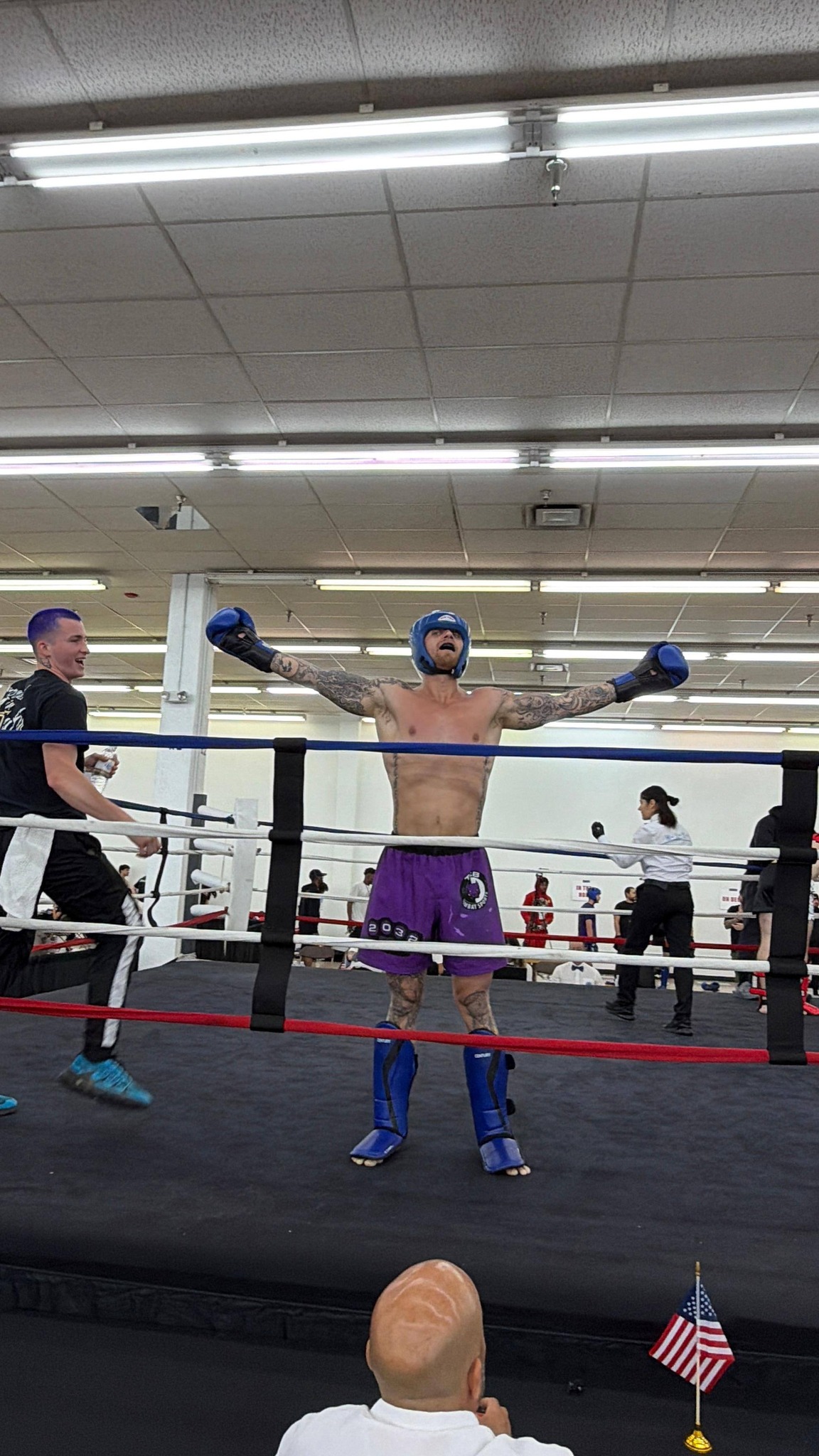 TCB fighter in blue head guard and purple shorts with arms raised in victory inside the ring at the 2026 WAKO USA Nationals